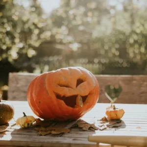 Smiling jack-o'-lantern with small pumpkins outdoors